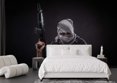 Hacker with gun over laptop on black background Wall mural